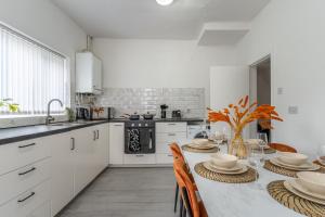een keuken met witte kasten en een tafel met stoelen bij Modern 4bedroom Spacious Family Home in Liverpool