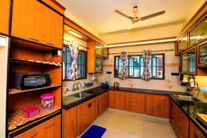 a large kitchen with wooden cabinets and a ceiling fan at Bay Homes 2BHK WT Bathtub Near Rock Beach in Puducherry