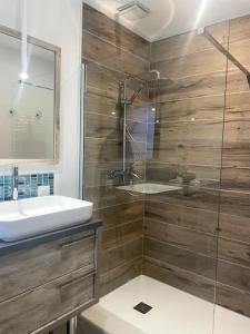 La salle de bains est pourvue d'un lavabo et d'une douche en verre. dans l'établissement Pavillon d'Éole, à Berck-sur-Mer