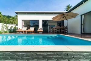 a swimming pool with an umbrella next to a house at Eden villas in Nathon Bay