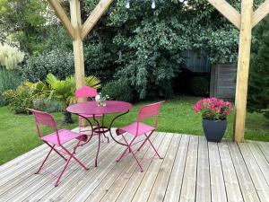 une table et des chaises roses sur une terrasse en bois dans l'établissement Pavillon d'Éole, à Berck-sur-Mer