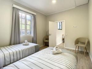 two beds in a room with a window and a chair at Solarium Villa by Atlantic Holiday in Machico