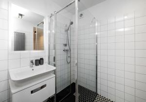 La salle de bains blanche est pourvue d'un lavabo et d'une douche. dans l'établissement Well located cozy place, à Lviv