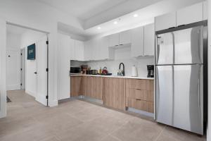 a kitchen with white cabinets and a stainless steel refrigerator at Roami at Metro Park in Miami