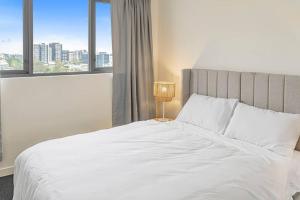 a bedroom with a large white bed with a window at Bowen Hills 1 Bedroom Apartment in Brisbane