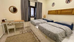 a bedroom with two beds and a desk and a mirror at Carob Hostel in Amman