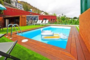 a large swimming pool with a wooden deck and a swimming pool at La Casa de Arriba in Arucas