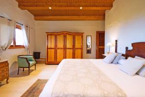 a bedroom with a large white bed and a chair at La Casa de Arriba in Arucas +23 photos