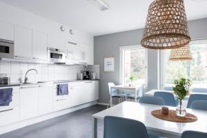 a kitchen and dining room with white cabinets and blue chairs at Linnéplatsens Hotell & Vandrarhem in Gothenburg
