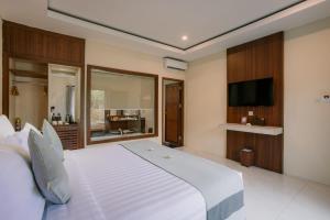 a bedroom with a large white bed and a flat screen tv at Ombak Sunset in Gili Trawangan