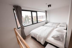 two beds in a room with a window at K&Y suites 2 ,500m to Brussels airport! in Zaventem