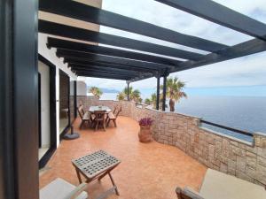 a patio with a table and chairs and the ocean at Apartamento Faro de Sardina in Gáldar
