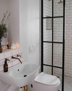 a white bathroom with a toilet and a sink at The Sugarbush in Cape Town