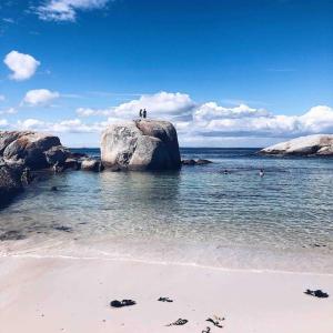 two people standing on a rock on the beach at The Sugarbush in Cape Town