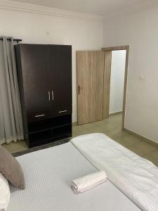 a bedroom with a large white bed with a dresser at Novara Apartments in Lekki