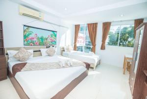 Dieses weiße Zimmer verfügt über 2 Betten und einen TV. in der Unterkunft Happy 99 Guest house in Patong Beach