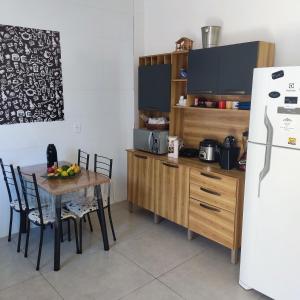 uma cozinha com uma mesa com cadeiras e um frigorífico em 2 suítes c/ Ar, Piscina, Churrasqueira, 500mt Mar em Santa Cruz Cabrália