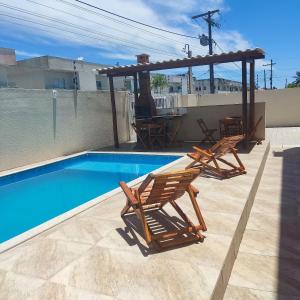 uma piscina com duas cadeiras e um gazebo em 2 suítes c/ Ar, Piscina, Churrasqueira, 500mt Mar em Santa Cruz Cabrália