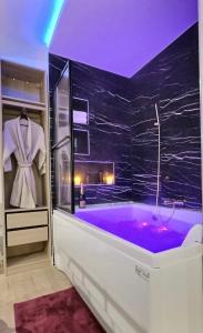 a bathroom with a purple tub with a black wall at Relax Room proche PARIS Porte de Versailles in Malakoff