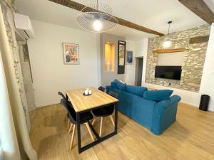a living room with a blue couch and a table at L'intemporel - Grand T2 climatisé & terrasse in Castres
