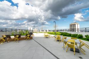a patio with yellow chairs and tables on a roof at All You Need in Curitiba