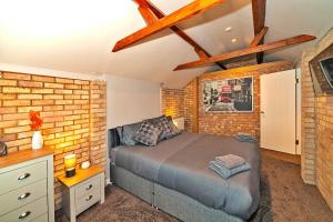 Finest Retreats - Chocolate Box Cottage في Potton: غرفة نوم بسرير وجدار من الطوب