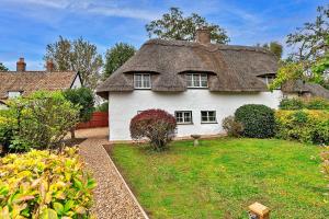 Finest Retreats - Chocolate Box Cottage في Potton: athtched house with a thached roof in a yard