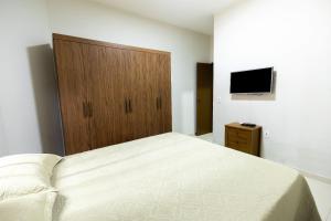 1 dormitorio con 1 cama y armario de madera en Casa Temporada Guriri Pé na areia!, en São Mateus