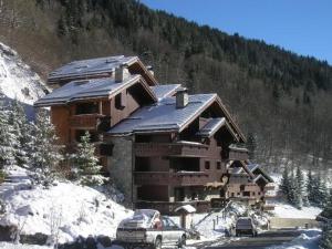 a ski lodge with cars parked outside of it in the snow at Confort et commodités à Méribel Village, 3 chambres, balcon sud, parking couvert, à 150m des remontées - FR-1-180-528 in Chandon
