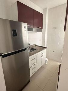 uma cozinha com um frigorífico de aço inoxidável e armários brancos em Apto no centro de Bertioga em Bertioga