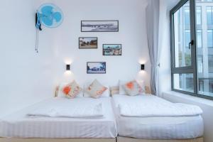トゥイホアにあるThành Tính Hotel - Khách sạn Phú Yênの窓のある白い部屋にベッドが2つある