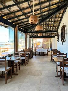 un restaurante con mesas de madera, bancos y ventanas en Pousada Morena, en Morro de São Paulo