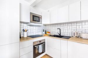 - une cuisine blanche avec évier et four micro-ondes dans l'établissement LA BELLE ROSE - Appartement 4 personnes proche gare Bordeaux, à Bègles