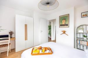 - une chambre blanche avec un plateau de fruits sur un lit dans l'établissement LA BELLE ROSE - Appartement 4 personnes proche gare Bordeaux, à Bègles
