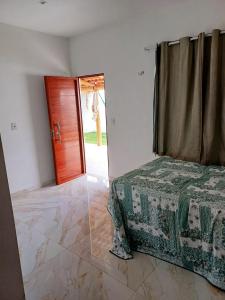 um quarto com uma cama e uma porta de madeira em Cantinho da Praia do Meio em São José de Ribamar