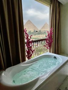 a bath tub in front of a window with pyramids at Unique Pyramids View INN in Cairo