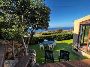 a patio with a table and chairs and the ocean at Casa Li Cossi vicino al mare in Costa Paradiso