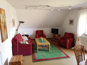 a living room with two red chairs and a table at Ferienwohnung-im-Gruenen-zwischen-Binz-und-Sellin in Zirkow