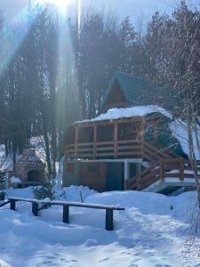 a log cabin in the snow with the sun behind it at Eko katun Mirac in Danilovgrad