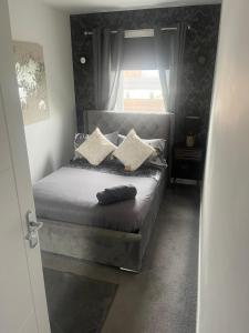 1 dormitorio con cama con almohadas y ventana en holiday apartment, en Ardrossan