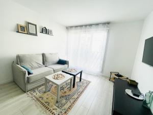 ein Wohnzimmer mit einem Sofa und einem Tisch in der Unterkunft Cosy appart proche Paris in Saint-Denis