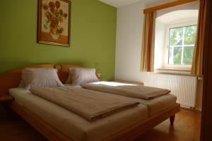 een bed in een groene kamer met een raam bij HOCHFICHTBLICK Apartments in Ulrichsberg