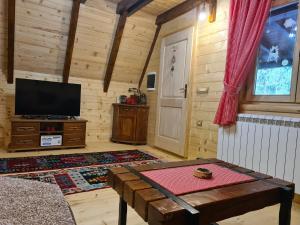 a living room with a tv and a table and a door at Eko katun Mirac in Danilovgrad