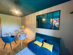 ein Wohnzimmer mit einem blauen Sofa und einem Schreibtisch in der Unterkunft Chambre calme Ouest Lyonnais in Lentilly