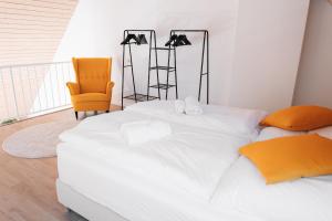 1 dormitorio con 1 cama blanca grande y 1 silla amarilla en Maisonette-Wohnung Airport/Messe Stuttgart - Balkon - Parkplatz - Netflix en Filderstadt