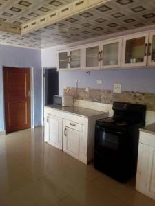 a kitchen with white cabinets and a black stove at Faigib Guest House in Chipata