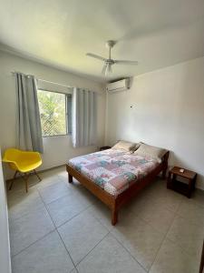 a bedroom with a bed and a yellow chair at Residencial Mansur - Jurerê in Florianópolis