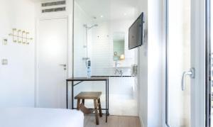 a white bathroom with a shower and a table at Hôtel Emile Le Marais in Paris