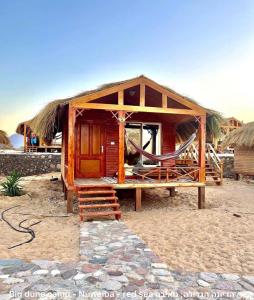 eine kleine Hütte mit Hängematte am Strand in der Unterkunft Big Dune camp in Nuweiba