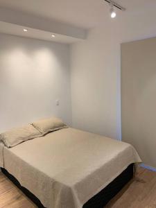 a bed in a room with a white wall at Apartamento Brooklin, próximo ao metrô Campo Belo in São Paulo